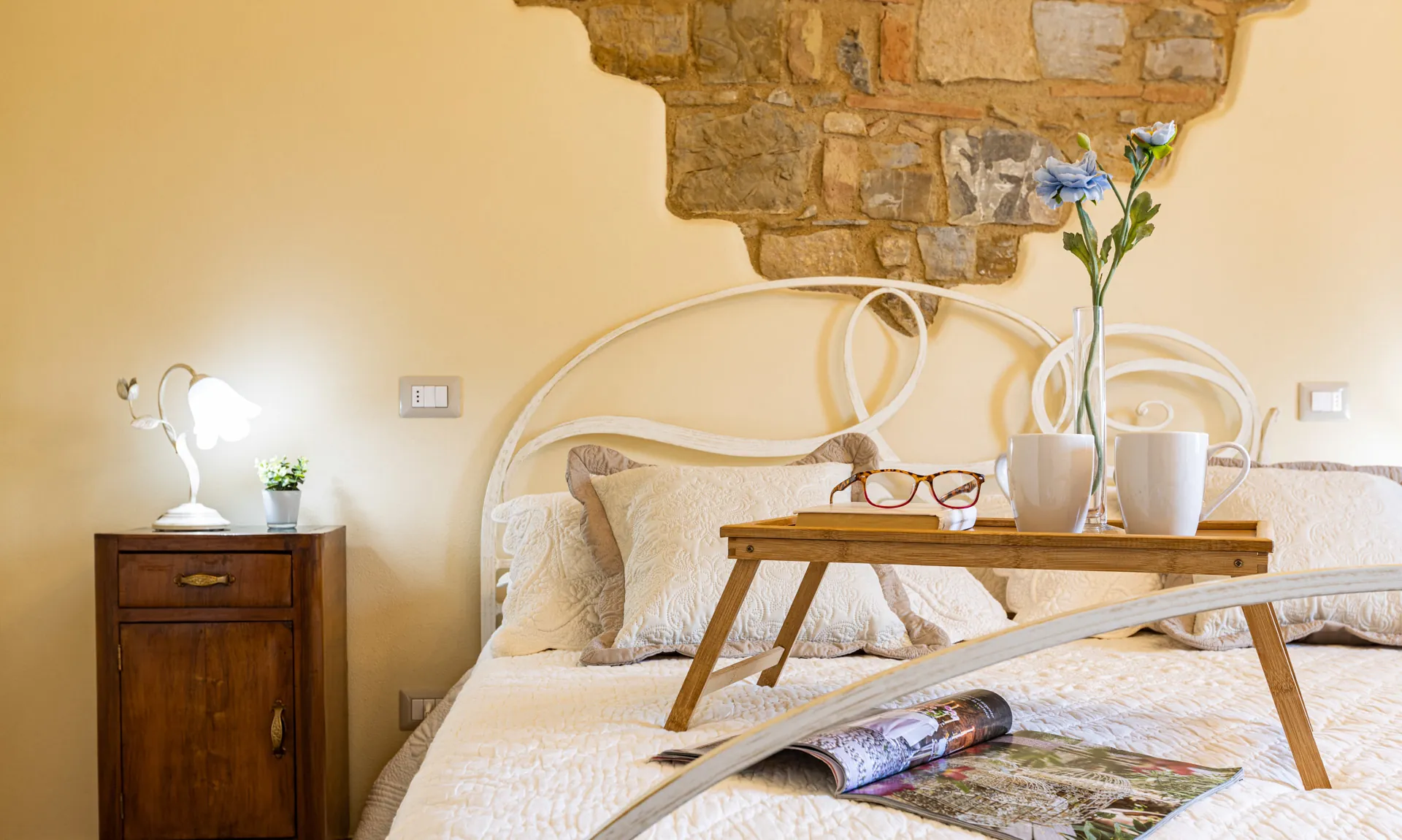 Double-bed with bedside table of Mimosa room at Tenuta di Macericca holiday farm